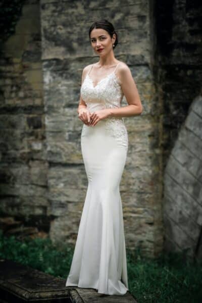 A Woman in White Wedding Dress Standing Near Brick Wall